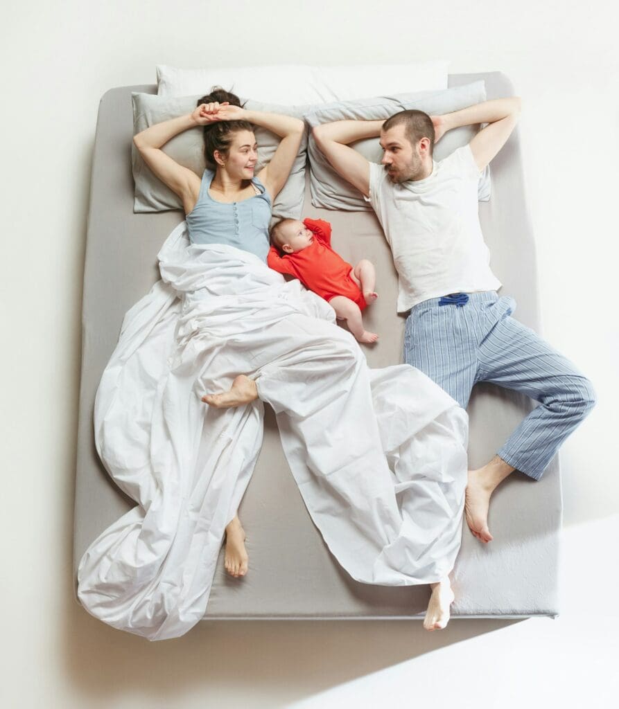Top view of happy family with one newborn child in bedroom.