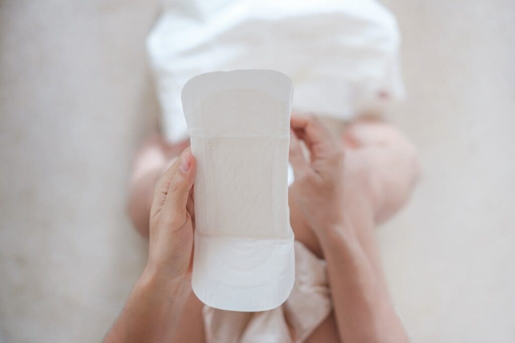 woman hands holding sanitary pad or menstruation napkin during wearing it. Menses, feminine